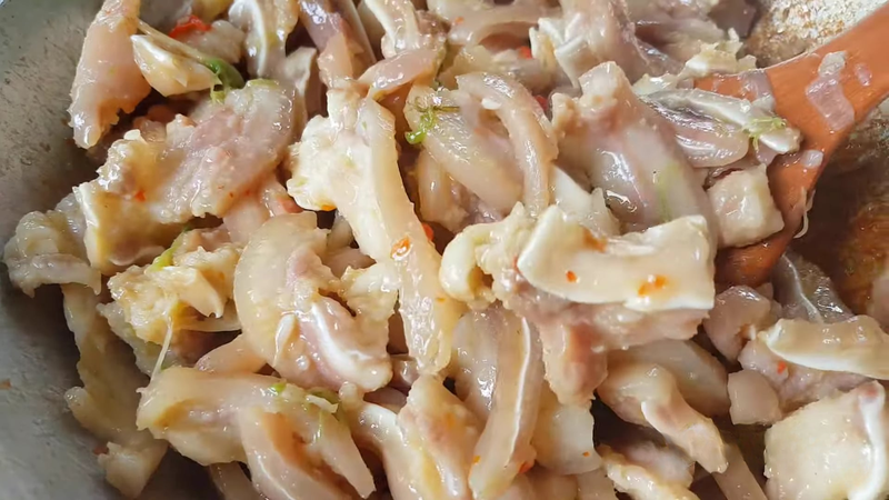 Cho tai heo đã ướp vào chảo, xào sơ cho săn lại rồi đổ nước dừa tươi vào khìa
