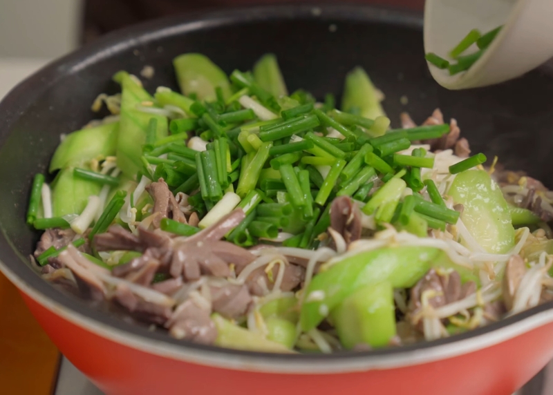 Đổ giá, hành lá đã sơ chế vào chảo