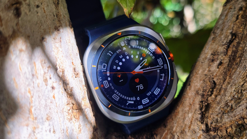 Chiếc Galaxy Watch Ultra tựa trên thân cây tự nhiên, đón ánh nắng ngoài trời làm nổi bật mặt số đa tính năng.