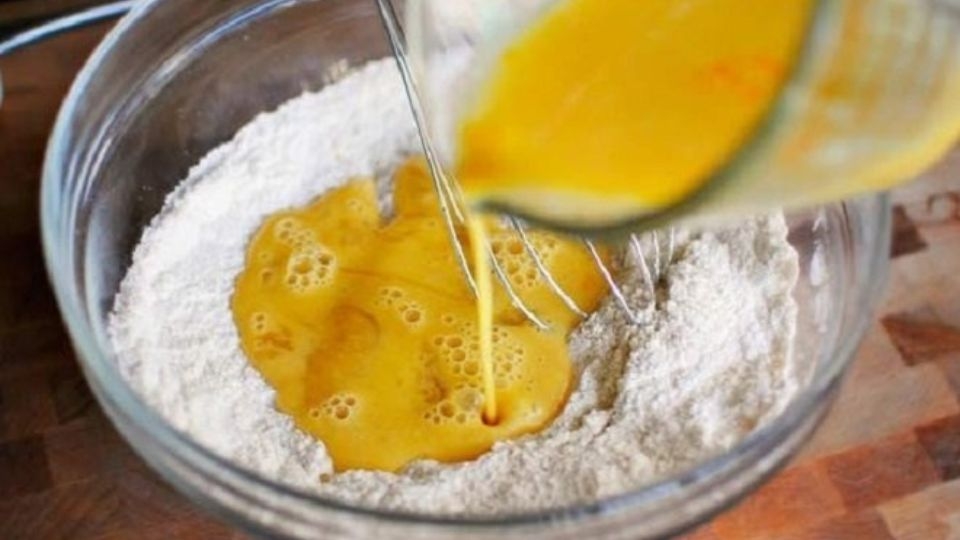 Lọc phần trứng gà đã chuẩn bị ở bước trước rồi rây vào hỗn hợp bột.