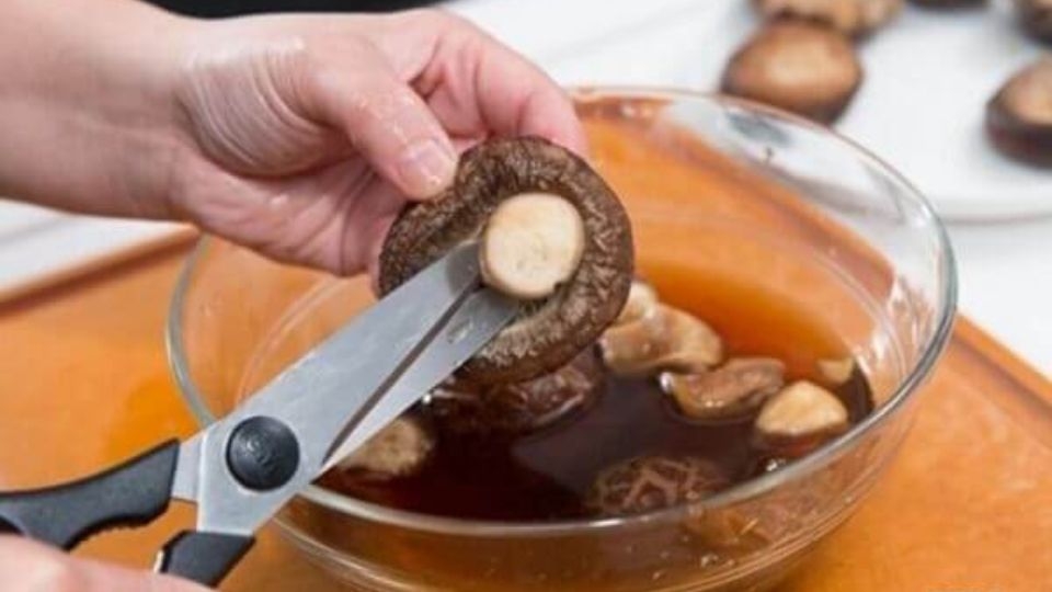Sau khi ngâm, bạn cắt bỏ cuống của nấm và rửa lại, để ráo nước.