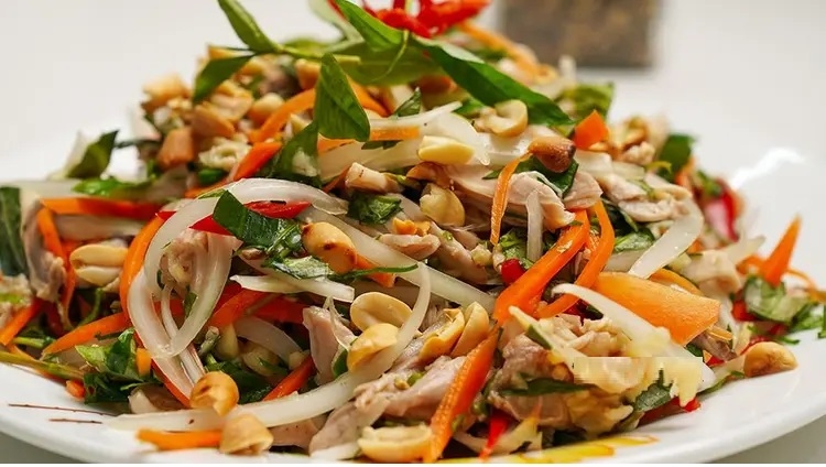Finished plate of Vietnamese chicken salad garnished with herbs and peanuts