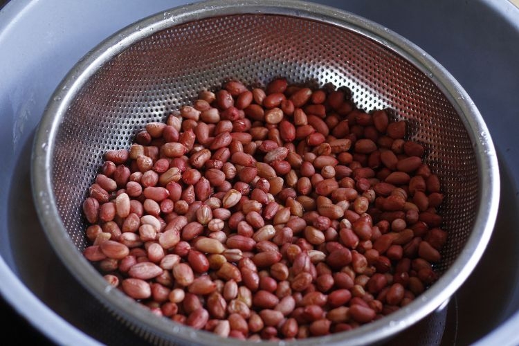Ngâm lạc trong nước sôi để loại bỏ bụi bẩn, nấm mốc