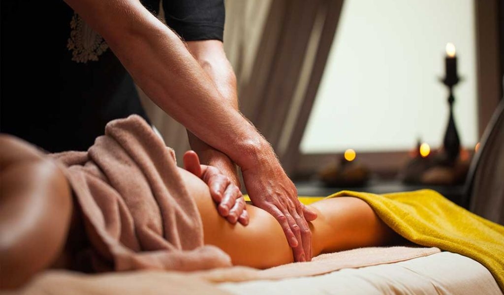 Người đang thực hiện massage chân trong không gian thoải mái với ánh nến lung linh.
