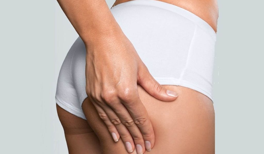 Người mặc đồ lót trắng, tay đặt lên đùi, nền màu xám nhạt.