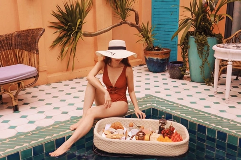 Tạo dáng chụp ảnh ăn sáng bên bể bơi.