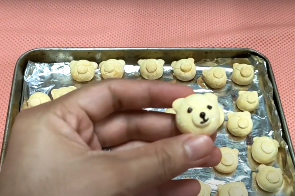 Dùng tăm chấm chocolate đen rồi vẽ mắt và miệng cho những chiếc bánh gấu.