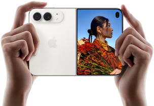 iPhone Duo, màu Trắng Ánh Sao, được cầm bằng hai tay theo hướng ngang, đang mở ra, màn hình bên trái hiển thị camera sau Dual Fusion 48MP, màn hình bên phải hiển thị một người đang chụp ảnh trên màn hình ngoài, chủ thể trong ảnh chụp có thể nhìn thấy khuôn mặt của chính mình khi ảnh được chụp bằng tính năng Duo Preview